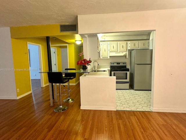 kitchen featuring visible vents, baseboards, under cabinet range hood, light wood finished floors, and stainless steel appliances
