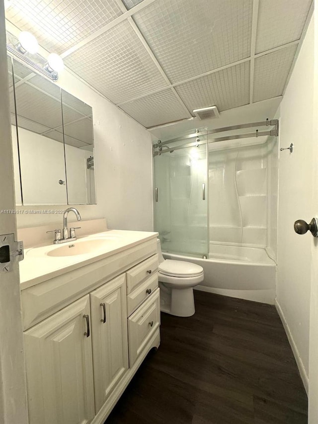 bathroom featuring vanity, toilet, visible vents, bath / shower combo with glass door, and wood finished floors
