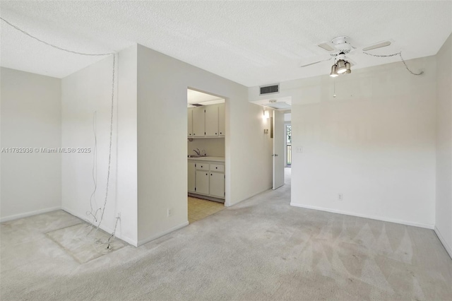 spare room featuring baseboards, visible vents, light colored carpet, and a ceiling fan