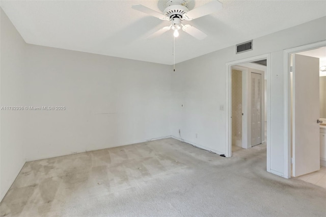 empty room with visible vents, light colored carpet, and ceiling fan