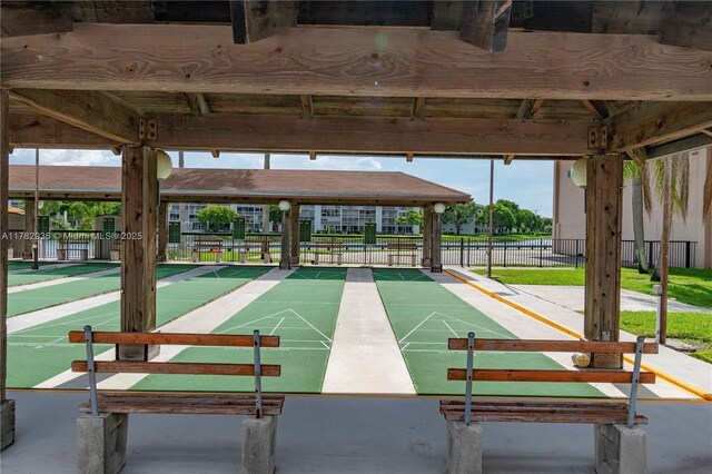 view of community featuring fence and shuffleboard