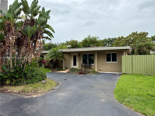 single story home with driveway, stucco siding, and fence