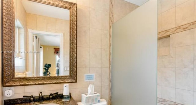 bathroom with a sink, backsplash, and tile walls