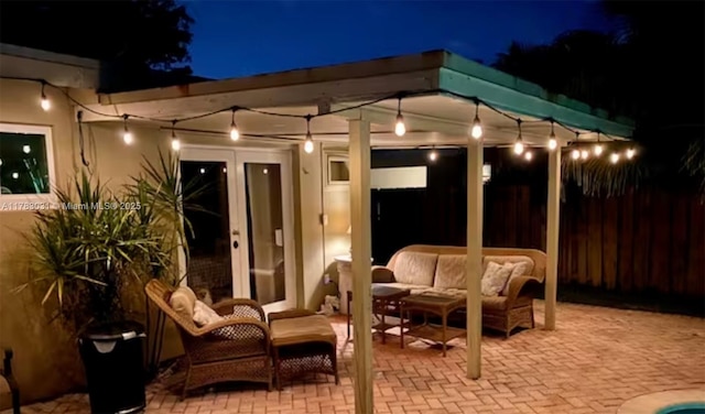 patio at night with an outdoor living space, french doors, and fence