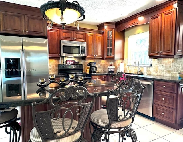 kitchen with a kitchen bar, appliances with stainless steel finishes, decorative backsplash, and glass insert cabinets