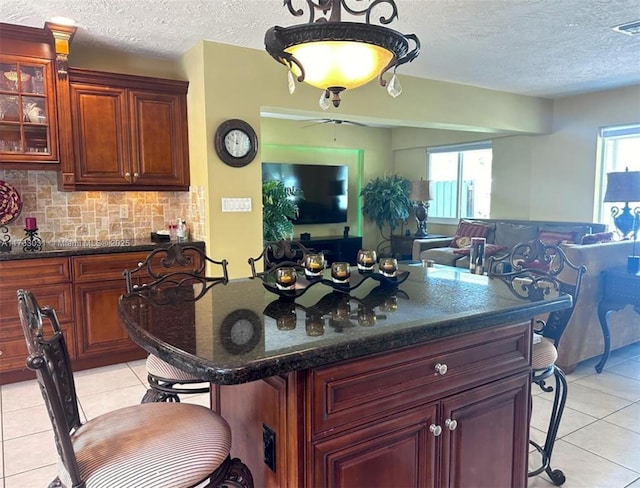 kitchen with open floor plan, light tile patterned flooring, a kitchen bar, and a textured ceiling