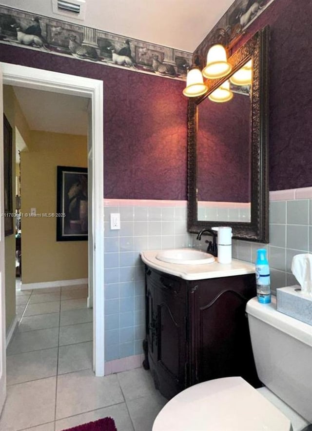 bathroom featuring toilet, tile walls, tile patterned flooring, and a wainscoted wall