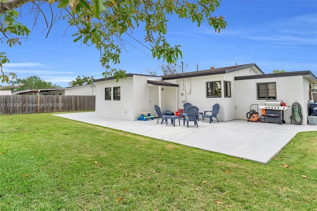 rear view of property featuring a lawn, a patio, stucco siding, and fence