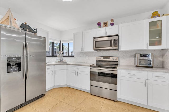 kitchen featuring appliances with stainless steel finishes, a sink, white cabinetry, and light countertops