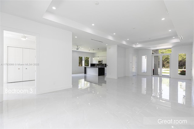 3802 30th Ave SE, Naples, FL 34117 - unfurnished living room featuring a tray ceiling, baseboards, recessed lighting, light marble finish floors, and ceiling fan