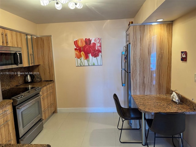 231 174th St Unit 2308, Sunny Isles Beach, FL 33160 - kitchen featuring brown cabinets, stainless steel appliances, dark stone countertops, a breakfast bar, and baseboards
