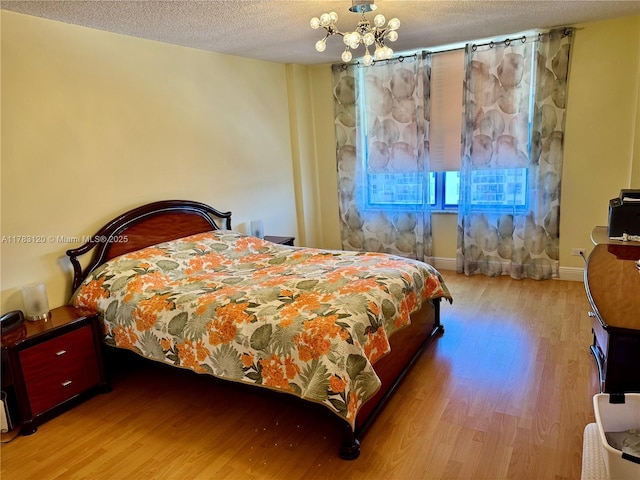 231 174th St Unit 2308, Sunny Isles Beach, FL 33160 - bedroom featuring baseboards, wood finished floors, a textured ceiling, and a chandelier