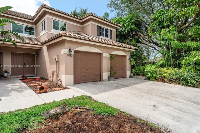 mediterranean / spanish-style home featuring a tiled roof, a garage, stucco siding, and concrete driveway