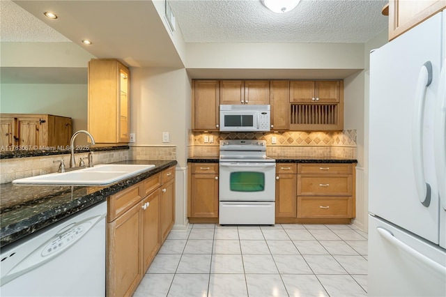 kitchen with tasteful backsplash, a sink, white appliances, a textured ceiling, and brown cabinets