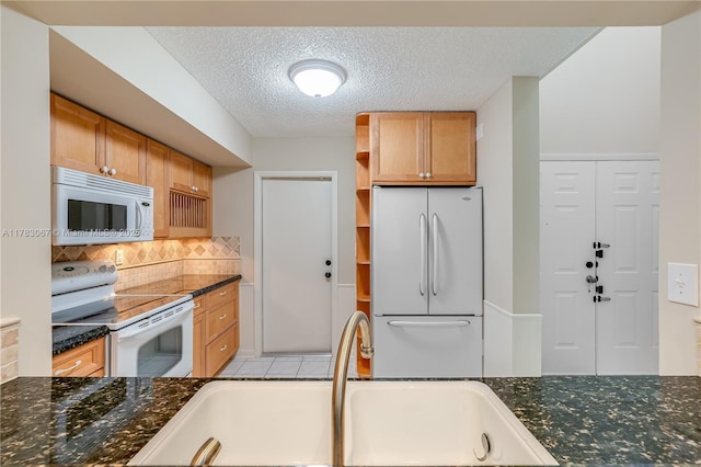 kitchen with white appliances, a textured ceiling, open shelves, a sink, and backsplash