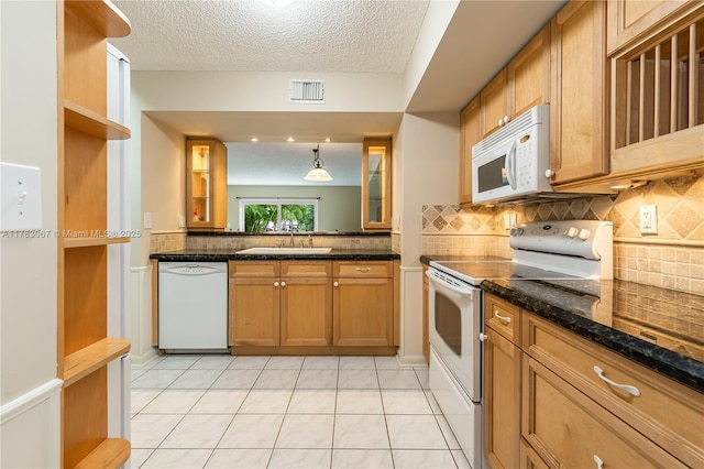 kitchen featuring tasteful backsplash, white appliances, visible vents, brown cabinetry, and a sink