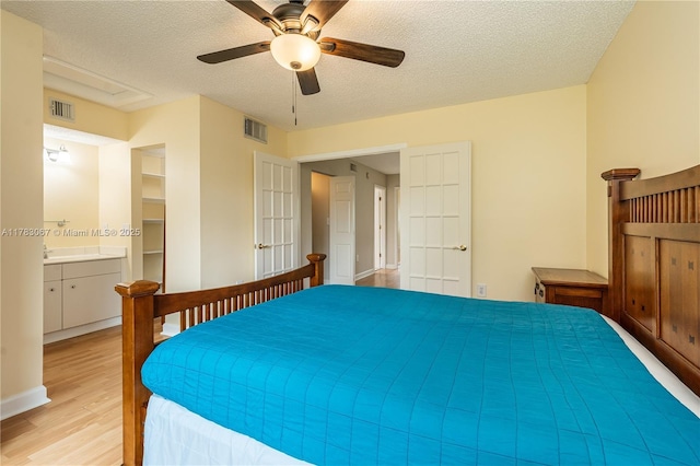 bedroom featuring light wood finished floors, visible vents, a textured ceiling, and french doors