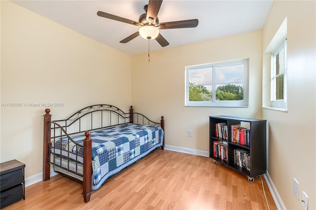 bedroom with light wood-type flooring, baseboards, and a ceiling fan