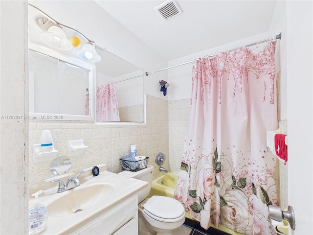full bath featuring toilet, tile walls, visible vents, shower / tub combo with curtain, and vanity