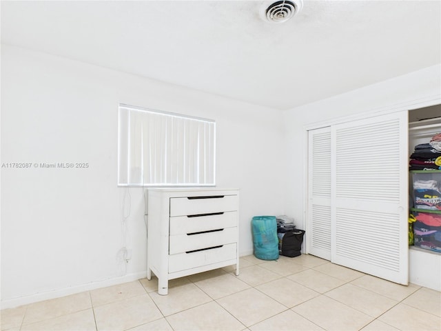 unfurnished bedroom featuring visible vents, a closet, and light tile patterned floors