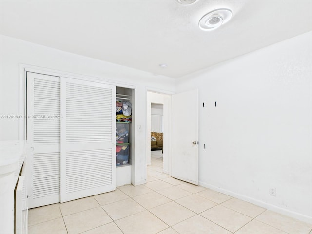 unfurnished bedroom with baseboards, light tile patterned flooring, and a closet