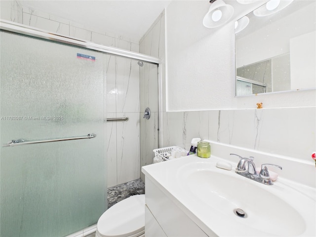 full bath with toilet, vanity, and a stall shower