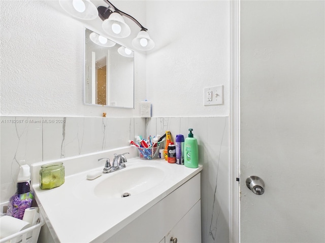 bathroom with tile walls, a wainscoted wall, and vanity