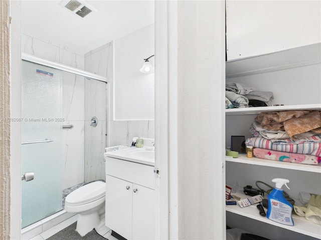 bathroom with vanity, visible vents, a shower stall, and toilet