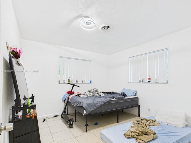 bedroom with visible vents, tile patterned floors, and baseboards