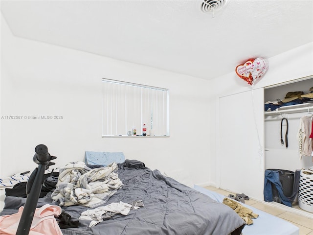 bedroom featuring tile patterned floors, visible vents, and a closet