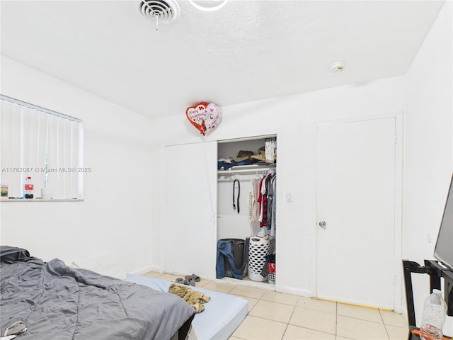 tiled bedroom with visible vents and a closet