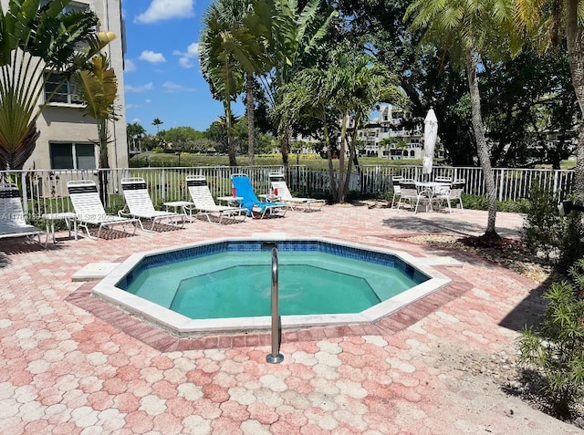 view of pool with a patio area, a community hot tub, and fence