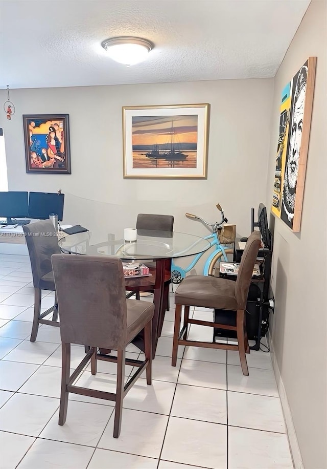 dining area with a textured ceiling, light tile patterned flooring, and baseboards