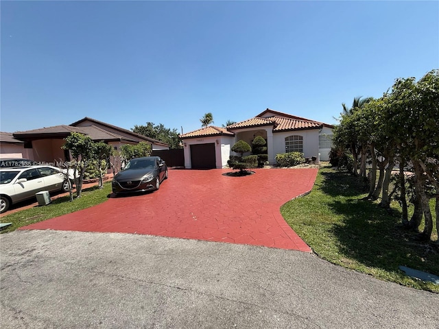 mediterranean / spanish-style house with stucco siding, decorative driveway, a front yard, a garage, and a tiled roof