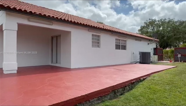 back of property featuring stucco siding, cooling unit, a patio area, a tiled roof, and a lawn