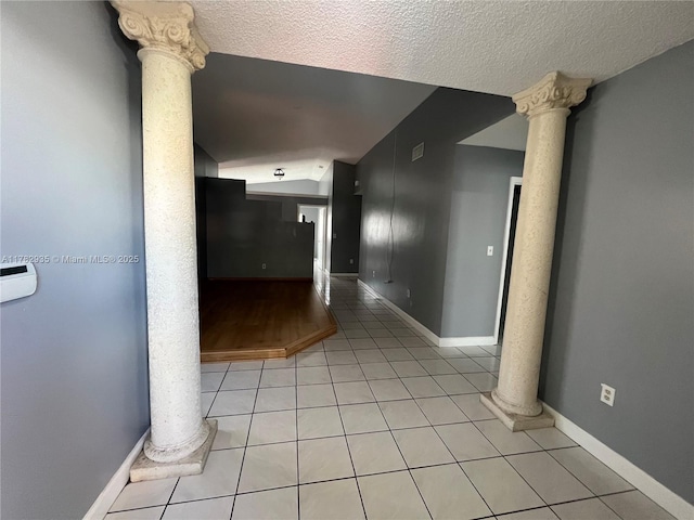 corridor featuring decorative columns, light tile patterned floors, a textured ceiling, and vaulted ceiling