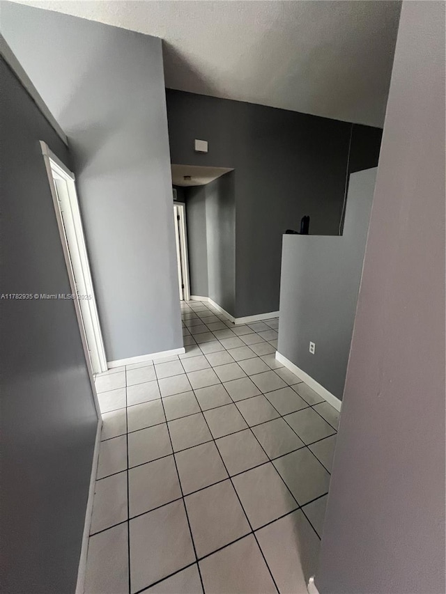 empty room with baseboards and light tile patterned flooring