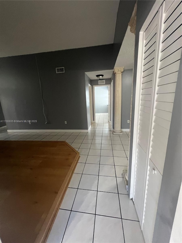 corridor featuring visible vents, baseboards, and light tile patterned flooring