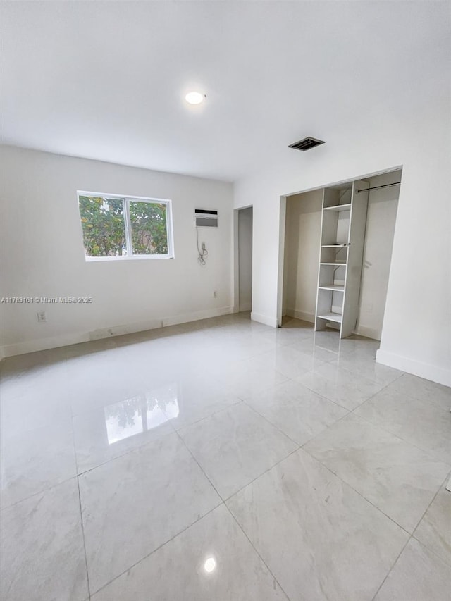unfurnished bedroom with baseboards, a wall mounted air conditioner, recessed lighting, and light tile patterned floors