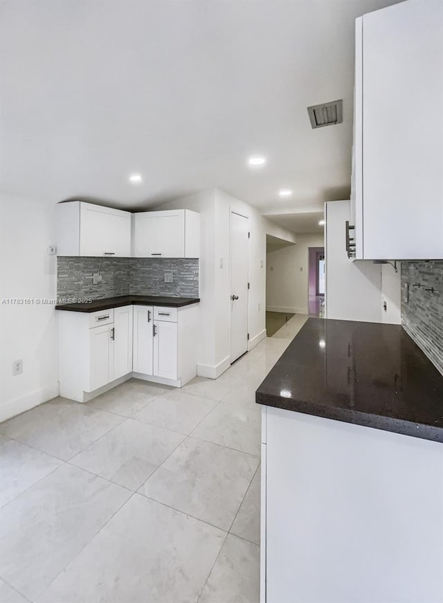 kitchen with decorative backsplash, dark countertops, white cabinetry, recessed lighting, and baseboards