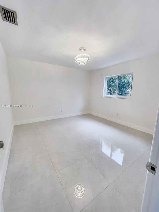 spare room with baseboards and light tile patterned flooring