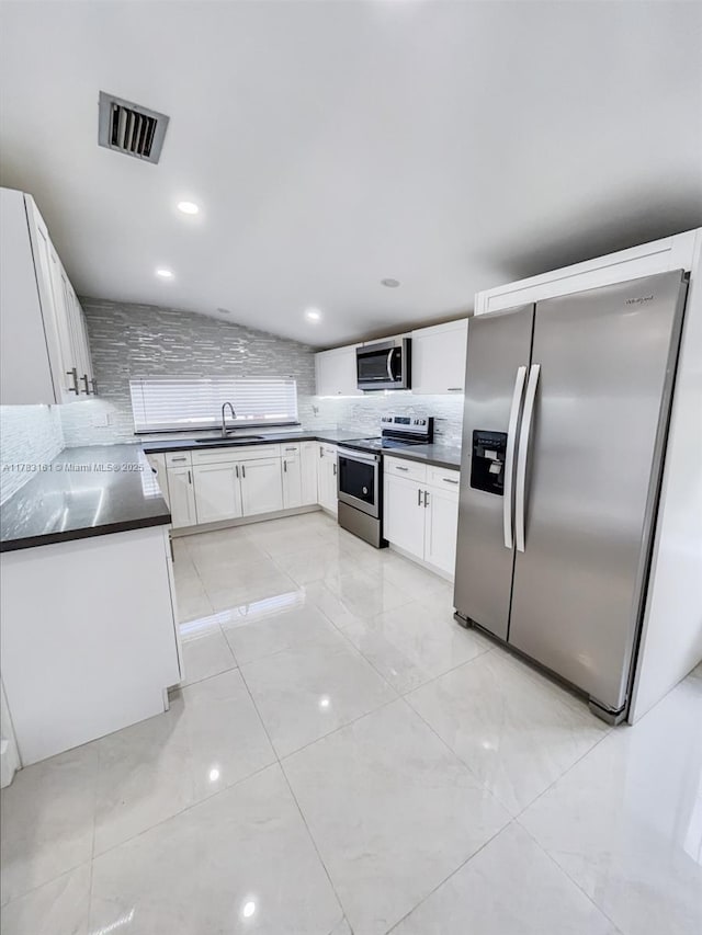 kitchen featuring stainless steel appliances, a sink, dark countertops, decorative backsplash, and lofted ceiling