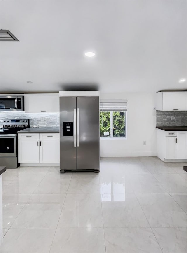 kitchen featuring appliances with stainless steel finishes, dark countertops, tasteful backsplash, white cabinets, and recessed lighting