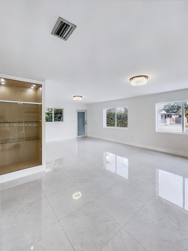 spare room featuring plenty of natural light, light tile patterned flooring, and baseboards