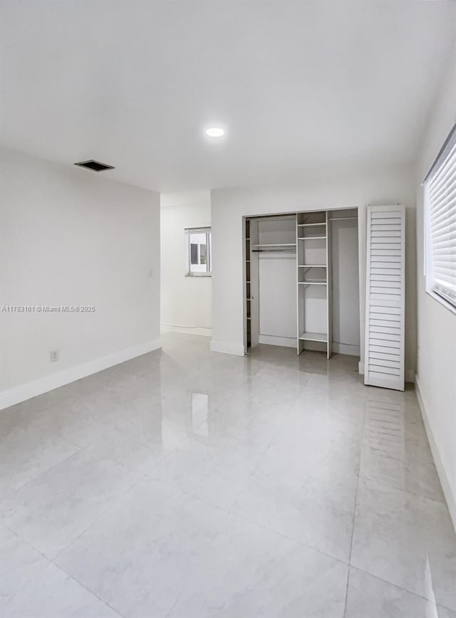 unfurnished bedroom featuring multiple windows, baseboards, recessed lighting, and a closet