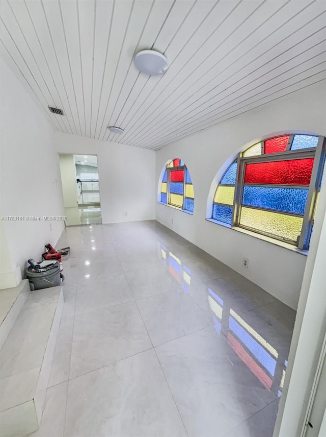 tiled empty room featuring wood ceiling