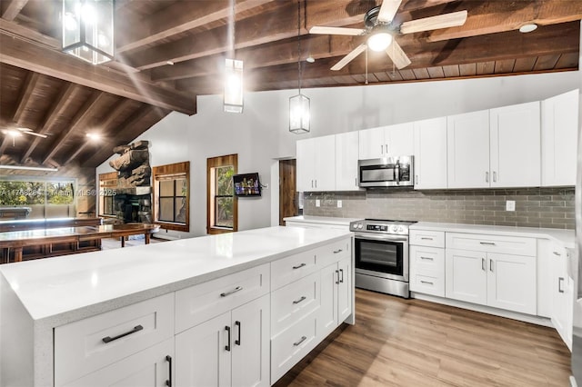 kitchen with stainless steel appliances, wood finished floors, decorative backsplash, and ceiling fan