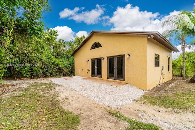 rear view of property featuring french doors, a patio area, and stucco siding