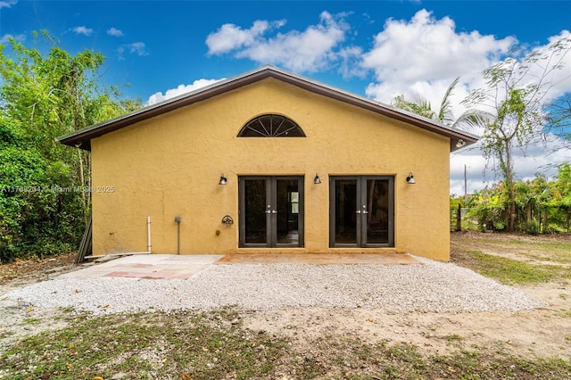 rear view of house featuring a patio area, french doors, and stucco siding