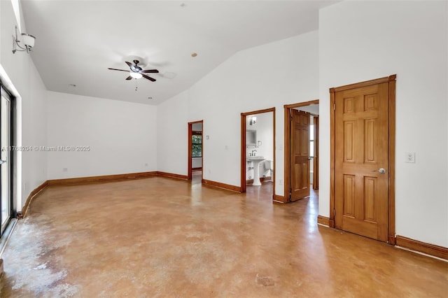 empty room with ceiling fan, high vaulted ceiling, finished concrete flooring, and baseboards